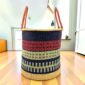 Open laundry basket with navy and red bands with a pale green check and tall leather handles