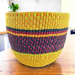 Vegan planter basket in bright warm tones with a deep checked middle band, on a timber table