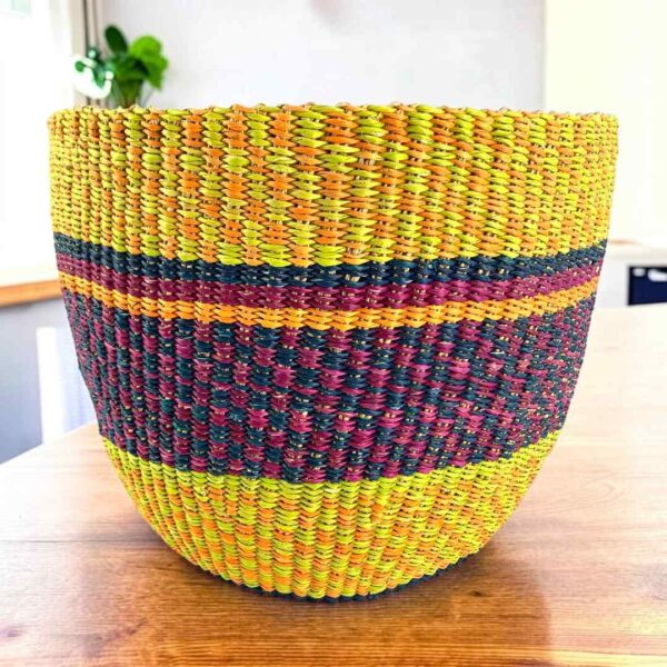 Vegan planter basket in bright warm tones with a deep checked middle band, on a timber table