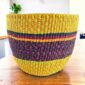 Vegan planter basket in bright warm tones with a deep checked middle band, on a timber table