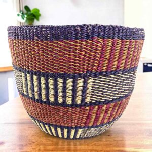 Vegan planter basket in earthy tones with bands of vertical stripes, on a timber table