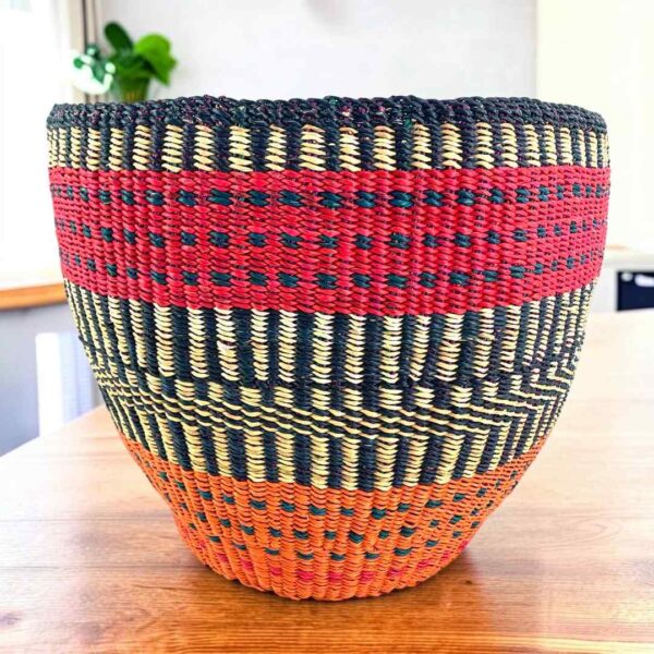Vegan planter basket with bold high-contrast stripes and a warm base, on a timber table