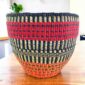 Vegan planter basket with bold high-contrast stripes and a warm base, on a timber table