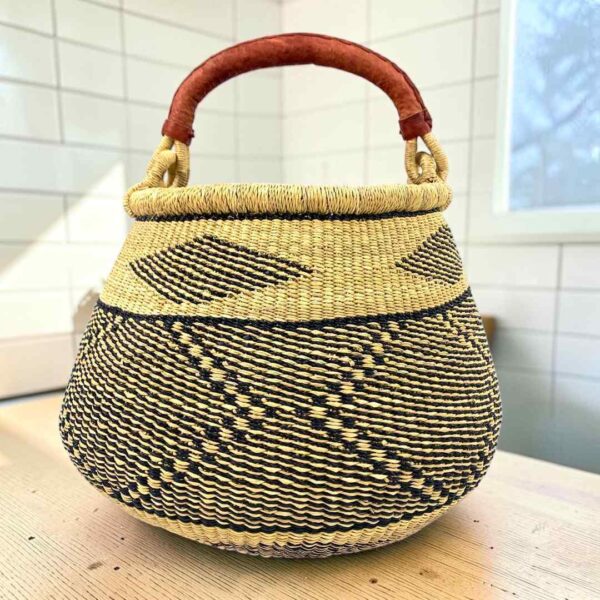 Bolga pot basket with a black and natural zigzag and diamond pattern and a leather-wrapped handle