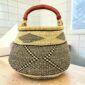 Bolga pot basket with a black and natural zigzag and diamond pattern and a leather-wrapped handle