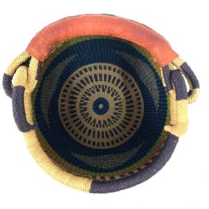 Top view inside the Bolga pot basket with orange, navy and green bands above a black and natural diagonal pattern and a leather-wrapped handle