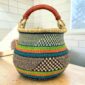 Bolga pot basket with green, orange and teal bands with a black and natural check and a leather-wrapped handle