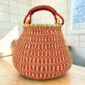Bolga pot basket with an orange-red and natural stepped pattern and a leather-wrapped handle