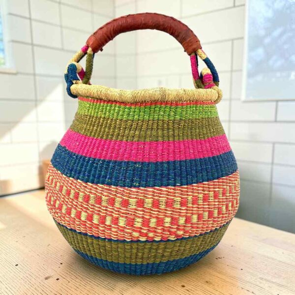 Bolga pot basket with pink, blue, olive and coral bands and a leather-wrapped handle