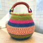 Bolga pot basket with pink, blue, olive and coral bands and a leather-wrapped handle