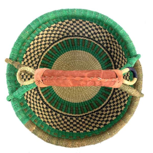 round-large-basket-856-radiance-green-brown-bolga-african-bashiri-2 Top-down view inside the large round Bolga basket with a fresh leafy band over a warm earthy checkerboard, showing the coiled base and leather handle