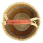 Top-down view inside the large round Bolga basket with warm amber tones and a dark diagonal checkerboard, showing the coiled base and leather handle