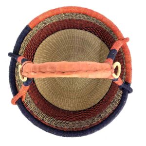 Top-down view inside the large round Bolga basket with deep red and inky diagonal sections, showing the coiled base and leather handle
