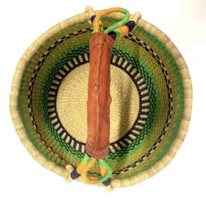 Top-down view inside the large round Bolga basket with fresh leafy tones and a band of deep inky checks, showing the coiled base and leather handle