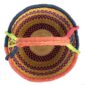 Top-down view inside the large round Bolga basket with bright citrus and rosy bands with deep inky checks, showing the coiled base and leather handle