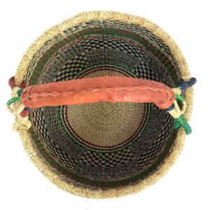 Top-down view inside the large round Bolga basket with fine dark checks and rust and leafy stripes, showing the coiled base and leather handle