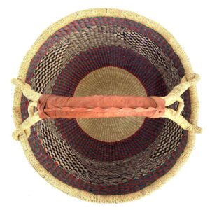 Top-down view inside the large round Bolga basket with a sea-green and berry band over fine inky patterning, showing the coiled base and leather handle