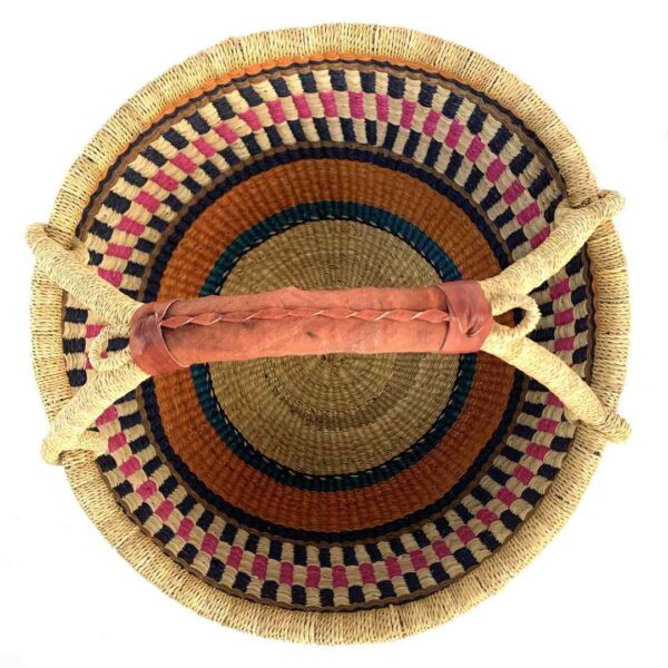 round-large-basket-869-inspire-orange-pink-navy-woven-bolga-bashiri-2 Top-down view inside the large round Bolga basket with warm burnt tones framing rosy and inky stripes, showing the coiled base and leather handle