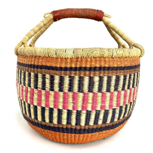 round-large-basket-869-inspire-orange-pink-navy-woven-bolga-bashiri-3 Front view of the large round Bolga basket with warm burnt tones framing rosy and inky stripes, on a white background
