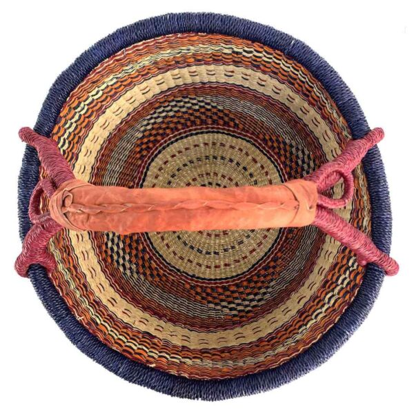 round-large-basket-870-abundance-navy-red-orange-bolga-woven-bashiri-2 Top-down view inside the large round Bolga basket with an inky rim over rust and amber patterning, showing the coiled base and leather handle