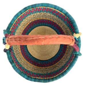 Top-down view inside the large round Bolga basket with deep sea-green bands and berry stripes, showing the coiled base and leather handle