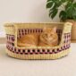 Small natural Bolga pet basket with pink and black checked bands and a ginger cat lying inside