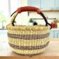 Small round Bolga basket with deep-toned stripes on a natural weave and leather-wrapped handle