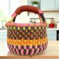 Small round Bolga basket with bold chequered bands in warm tones and leather-wrapped handle