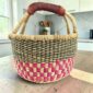 Handcrafted small round Bolga basket with reinforced leather handles and durable construction.