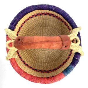 Top-down view inside the small round Bolga basket with red and purple checked bands on natural straw, showing the coiled base