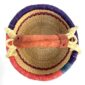 Top-down view inside the small round Bolga basket with red and purple checked bands on natural straw, showing the coiled base
