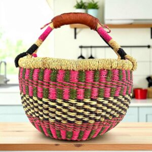 Small round Bolga basket with a checked pattern in warm, deep tones and leather-wrapped handle