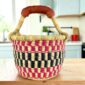 Small round Bolga basket with a bold chequered pattern in bright and dark tones and leather-wrapped handle