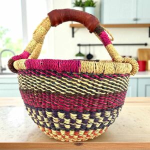 Small round Bolga basket with bands and checked detail in deep, warm tones and leather-wrapped handle