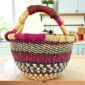 Small round Bolga basket with bands and checked detail in deep, warm tones and leather-wrapped handle
