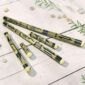 Bamboo rainsticks in multiple sizes, hand-painted with black and natural motifs, arranged on a white wooden surface.