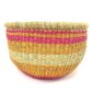 Front view of the round Bolga storage basket with pink, orange and yellow bands on natural straw and no handles on a white background