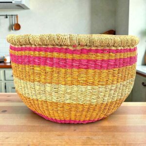 Round Bolga storage basket with pink, orange and yellow bands on natural straw and no handles