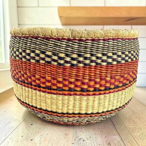 Round Bolga basket with no handles in orange and black, handwoven from elephant grass