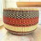 Round Bolga basket with no handles in orange and black, handwoven from elephant grass