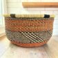 Round Bolga basket with no handles in rust and black, handwoven from elephant grass