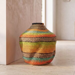 Bolga Wave Pot Basket in orange, teal and lime green woven bands, styled against a wall in natural light
