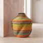 Bolga Wave Pot Basket in orange, teal and lime green woven bands, styled against a wall in natural light