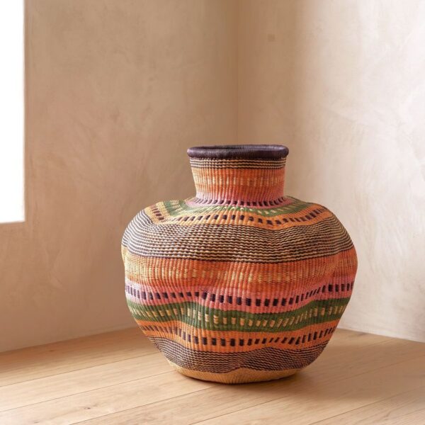 Bolga Wave Pot Basket in rust, olive green and pink woven bands, styled on a timber floor