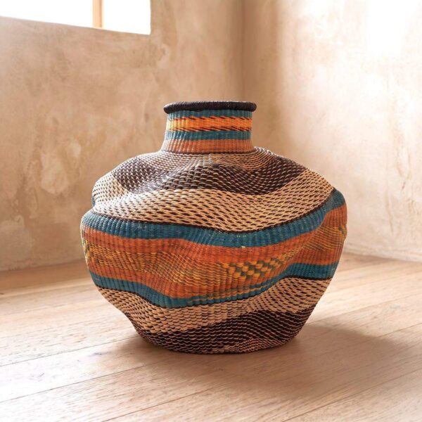 Bolga Wave Pot Basket in teal and rust woven bands, styled by a window on a timber floor