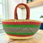 Red and green striped Mega Wawa Bolga basket with a black zigzag panel and two leather handles, on a wooden table