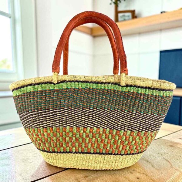 wawa-basket-260-locco-main Mega Wawa Bolga basket in a speckled olive green and rust weave with two leather handles, on a wooden table