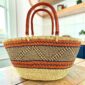 Mega Wawa Bolga basket with orange bands, a black and natural zigzag panel and two leather handles, on a wooden table