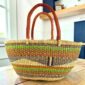 Lime and orange striped Mega Wawa Bolga basket with a black wave panel and two leather handles, on a wooden table